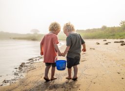 两个小男孩在海滩上带着一桶