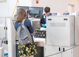 乘客通过TSA安全在纽约皇后区的拉瓜迪亚机场。TSA代理检查液体在一个女人的包。用佳能5 d Mark lV。